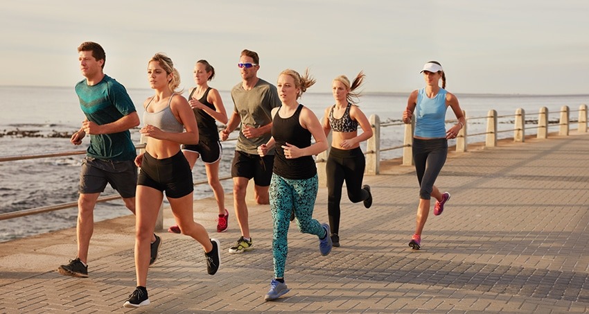 Young people running along beach boardwalk