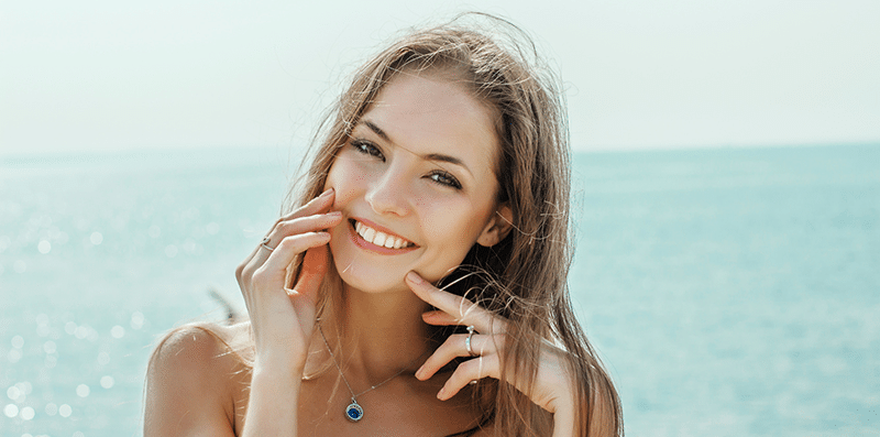 A young woman with a nice smile standing in fornt of open water