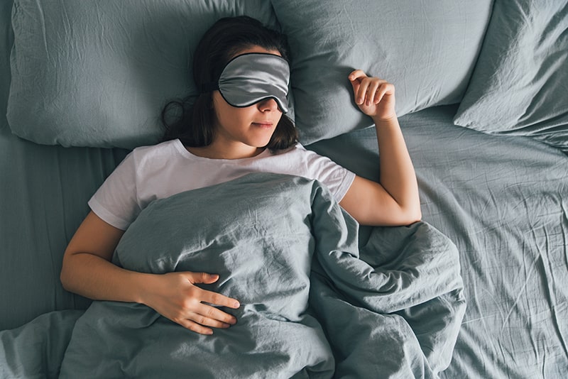A woman resting peacefully in bed with the help of Myofunctional Therapy for Sleep Apnea