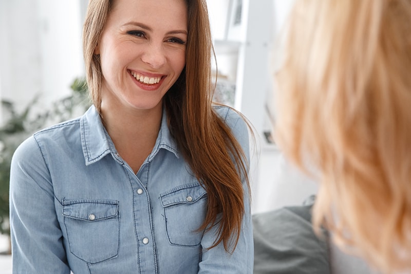 Young woman speaking with a friend regarding Myofunctional Therapy and how it can improver your Dental Health and Sleep Quality