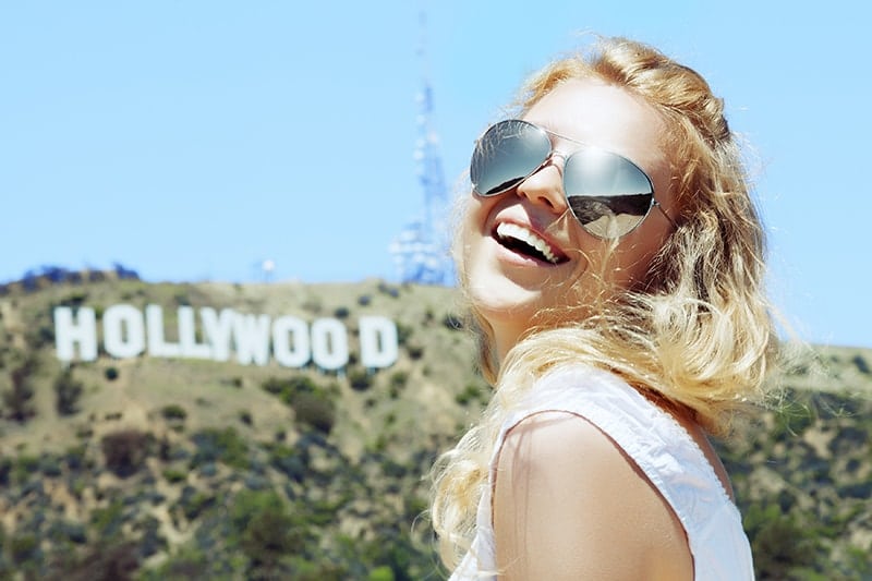 A pretty blonde woman in big sunglasses stands in front of the Hollywood sign. While Hollywood is the standard for cosmetic dentistry the new trend is a more natural, beautiful look to your smile. Learn how Dr. Marzban can make you beautiful!